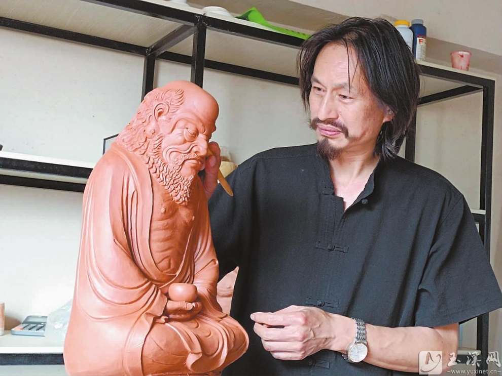 王华伟正在雕刻人物泥像。